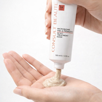 Hand holding a tube of Consult Beaute treatment mask with some product on the palm against a white background.  Microbiome Probiotic Reset Treatment Mask