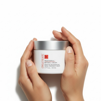 Hands holding a jar of Regenerol Retinol Cream against a white background.  White jar of Consult Beaute Regenerol Retinol Cream with silver lid on a white background.  Consult Beaute by Dr Terry Dubrow and Heather Dubrow.  