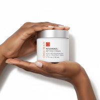 Two hands holding a container of Consult Beaute Regenerol Retinol Cream on a white background.  White jar of Consult Beaute Regenerol Retinol Cream with silver lid on a white background.  Consult Beaute by Dr Terry Dubrow and Heather Dubrow.  