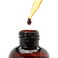 Amber glass dropper bottle with a drop of liquid being added on a white background